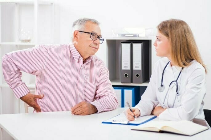 doctorAndPatient man in pain speaking with doctor about getting cervical facet injections