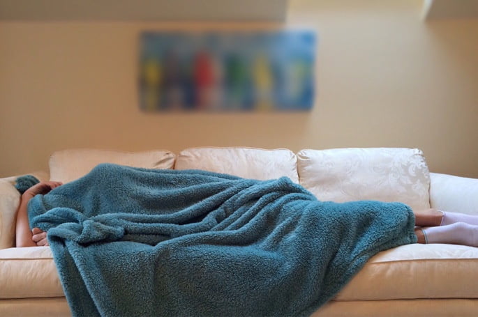sleepingOnCouch lumbar facet injection - person sleeping under blanket on couch