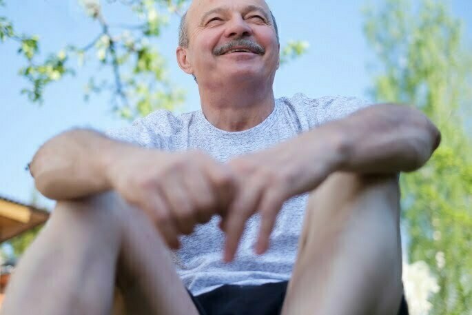 An Elderly Man Sitting Outside With a Smile