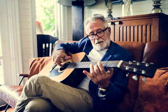 Man Playing The Guitar On Couch